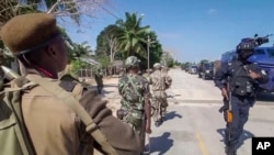 FILE -In this image made from video, a Rwandan policeman, right, and Mozambican military, left, patrol near the Amarula Palma hotel in Palma, Cabo Delgado province, Mozambique Sunday, Aug. 15, 2021.