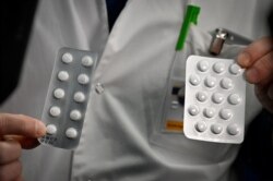 In this photo taken Feb. 26, 2020, medical staff at the IHU Mediterranee Infection Institute in Marseille, France, show packets of Nivaquine, tablets containing chloroquine, and Plaquenil, tablets containing hydroxychloroquine.