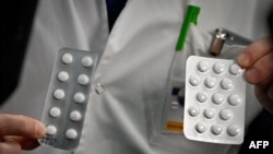 FILE - In this photo taken on Feb. 26, 2020, medical staff at the IHU Mediterranee Infection Institute in Marseille, France, show packets of Nivaquine, tablets containing chloroquine and Plaqueril, tablets containing hydroxychloroquine. 