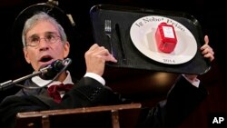 Master of Ceremonies Marc Abrahams holds up the 2014 Ig Nobel Prize trophy during a performance at the Ig Nobel Prize ceremony at Harvard University, in Cambridge, Mass., Sept. 18, 2014. 