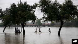 Boys play in the rain on a flooded street in Prayagraj, in the northern Indian state of Uttar Pradesh, Sept. 28, 2019. 