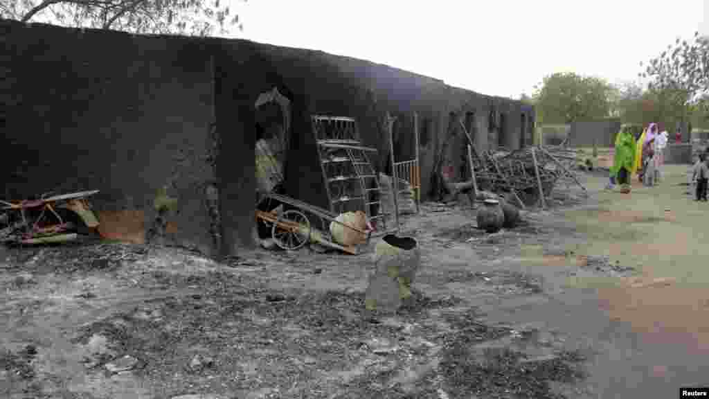 People walk past ashes in the aftermath of what Nigerian authorities said was heavy fighting between security forces and Islamist militants in Baga.