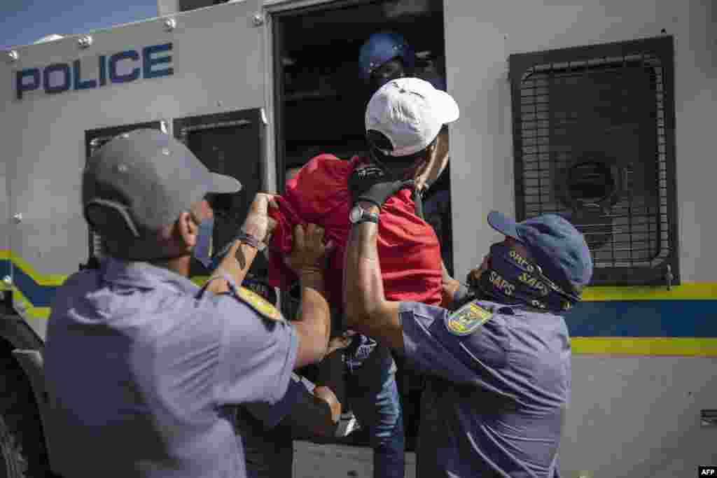 South African Police Service (SAPS) officers force a student member of the Economic Freedom Fighters (EFF) inside a police van during a protest in Braamfontein, Johannesburg.