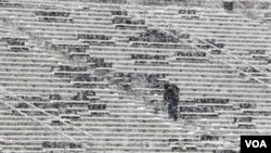 Un obrero limpia las gradas cubiertas de nieve en un estadio de fútbol en Pennsylvania.