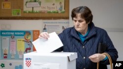 Seorang pemilih memasukkan surat suara di tempat pemungutan suara di Zagreb, Kroasia, 22 Desember 2019. 