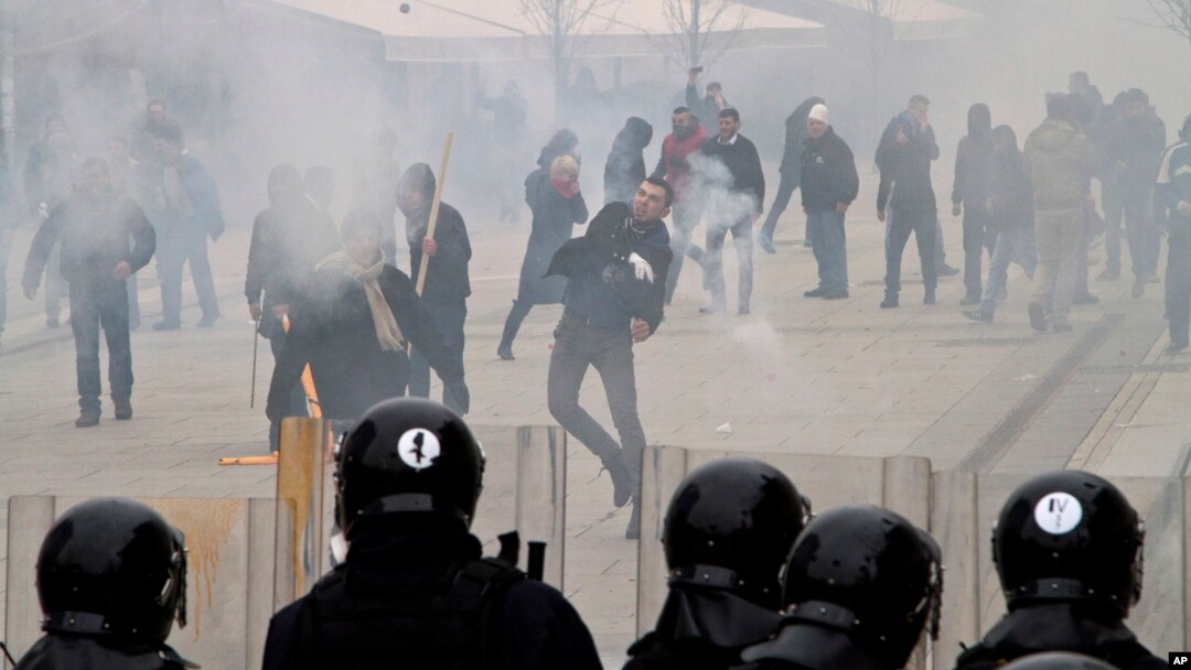 Učesnik demonstracija baca kamenicu na kordon policije, 27. januar 2015.