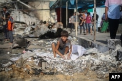 Seorang anak Palestina mengumpulkan tepung yang tumpah dari tanah di lokasi serangan udara Israel yang menghantam tenda-tenda pengungsi dua hari sebelumnya di halaman Rumah Sakit Syuhada Al-Aqsa di Deir al-Balah di Jalur Gaza tengah pada 16 Oktober 2024. (Foto: AFP)