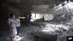 In this photo made on a government organized tour, Libyans inspect damage while standing next to an unexploded missile at the Gadhafi family compound in a residential area of Tripoli, Libya, May 1, 2011