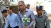 Philip Blackwood, second right, general manager of VGastro Bar, walks with bar owner Tun Thurein, second left, and its manager, Htut Ko Ko Lwin, seen behind Blackwood, upon arrival for their trial at a township court, Feb. 17, 2015.