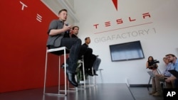 FILE - Elon Musk, CEO of Tesla Motors Inc., left, discusses the company's new Gigafactory in Sparks, Nevada, July 26, 2016. Tesla announced in September that it had been selected to build a battery storage project at the Mira Loma electricity substation in California's Riverside County.