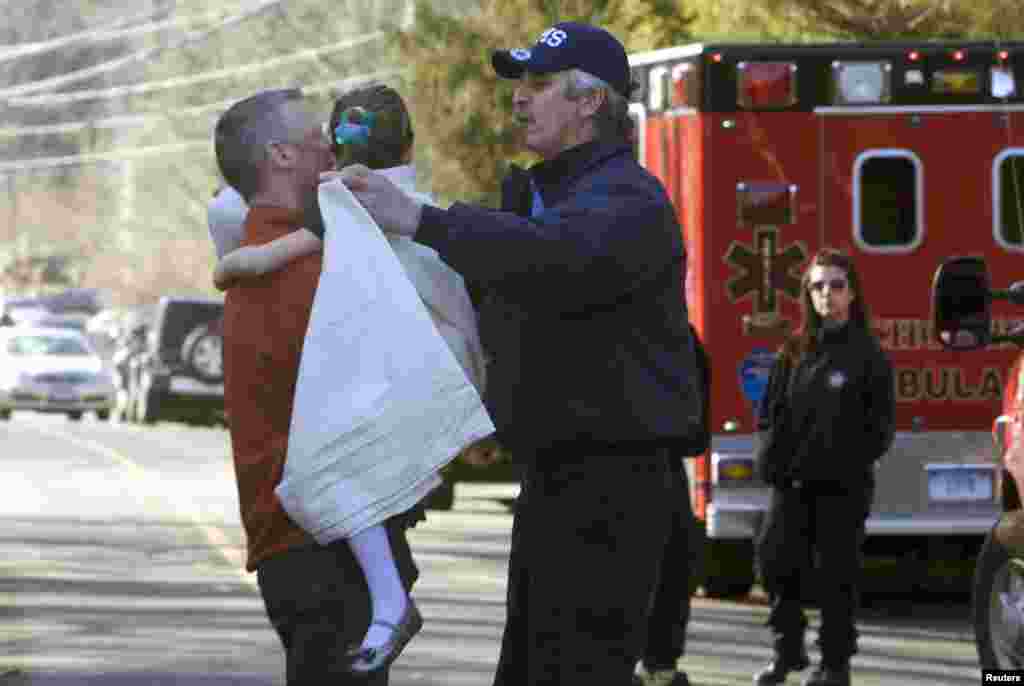 Una ni&ntilde;a es entregada envuelta en una frazada es entregada a su padre, luego de ser evacuada de la escuela. El pistolero mat&oacute; al menos a 27 personas, la mayor&iacute;a ni&ntilde;os. 