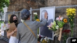 Orang-orang meletakkan bunga di samping foto Uskup Agung Anglikan Desmond Tutu di Katedral St. George di Cape Town, Afrika Selatan, 26 Desember 2021. (Foto: AP)