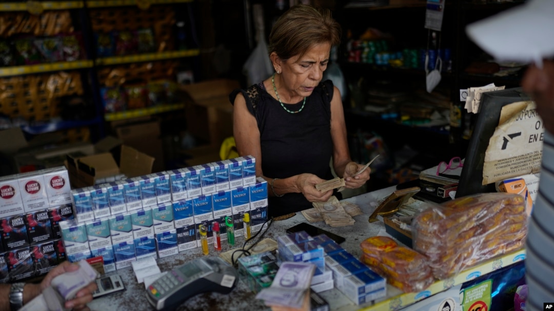 ARCHIVO - Una vendedora cuenta el pago de un cliente en un mercado en Valencia, Venezuela, el 1 de febrero de 2024.