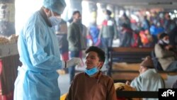 ভারতের জম্মুতে একটি বাস স্টেশনে একজন স্বাস্থ্যকর্মী কোভিদ-১৯ পরীক্ষা করার জন্য একজন যাত্রীর কাছ থেকে নমুনা সংগ্রহ করছেন।১৩ জানুয়ারী ২০২২। (ছবি-এপি/চান্নি আনন্দ)