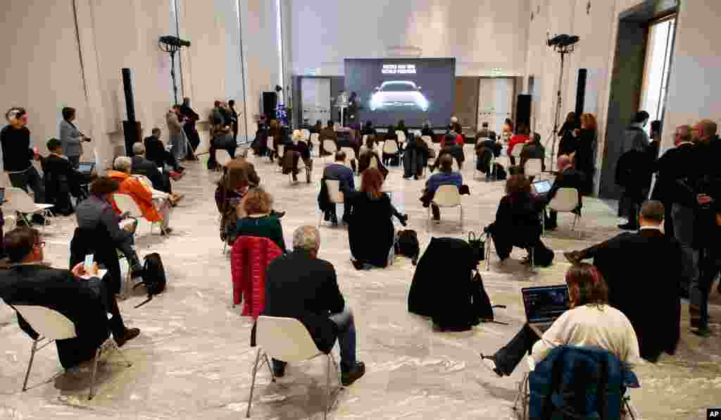 People sit a recommended distance apart from each other during a presentation of the new FIAT 500 electric car, in Milan, Italy. Countries are taking drastic and increasingly visible measures to curb the spread of the coronavirus. 