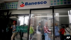 Un cliente sale de una sucursal bancaria de Banesco mientras otros hacen fila, en Caracas, Venezuela, el viernes 4 de mayo de 2018.