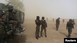 FILE - Cameroonian soldiers stand guard amidst dust kicked up by a helicopter in Kolofata, Cameroon, March 16, 2016. Part of a multinational force, the soldiers have intensified their fight against Boko Haram militants.