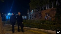 Plainclothes police officers pass by a primary school following a knife attack that occurred on an intersection road near a school in the northwestern Haidian district in Beijing, Oct. 28, 2024.