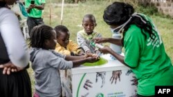 Un travailleur enseigne à plusieurs enfants comment se laver correctement les mains à l'entrée de l'hôpital Mbagathi de Nairobi, au Kenya, le 18 mars 2020. (Photo: LUIS TATO / AFP)