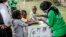 Un travailleur enseigne à plusieurs enfants comment se laver correctement les mains à l'entrée de l'hôpital Mbagathi de Nairobi, au Kenya, le 18 mars 2020.  (Photo: LUIS TATO / AFP)