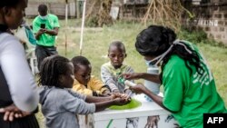 Seorang petugas memberikan pengarahan bagaimana cara mencuci tangan dengan benar untuk anak-anak di pintu masuk Rumah Sakit Mbagathi di Nairobi, Kenya, 18 Maret 2020. (Foto: dok).