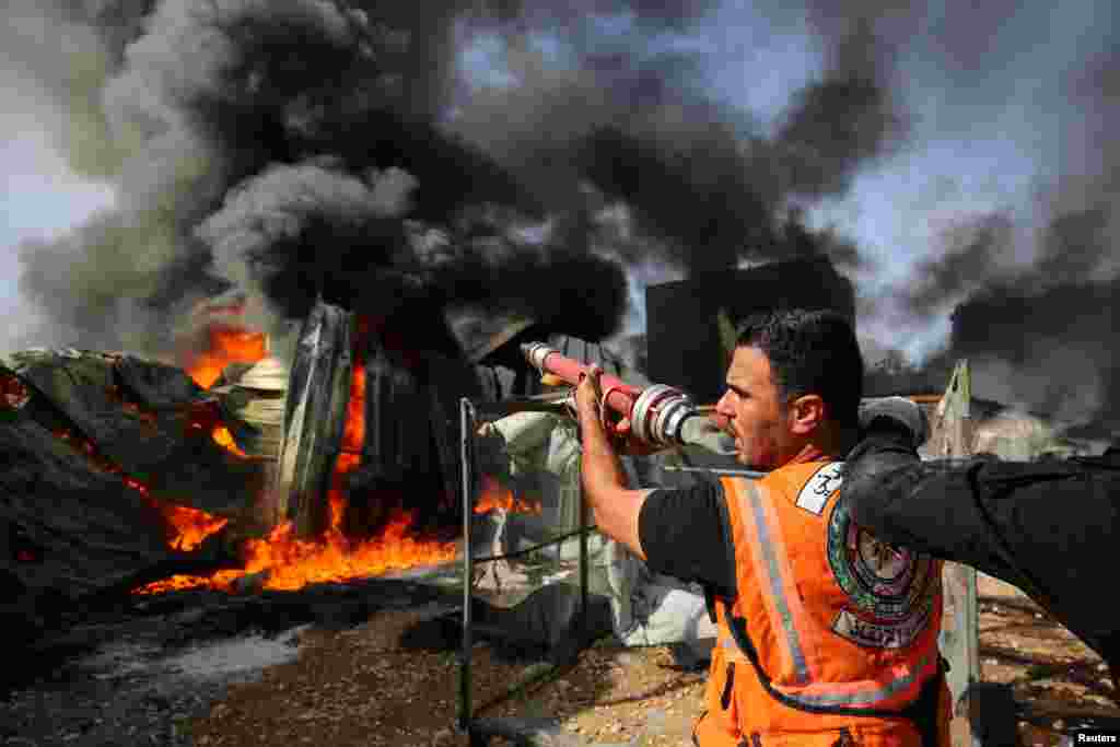 Un bombero palestino participa en los esfuerzos para apagar un incendio en una f&#225;brica de esponjas despu&#233;s de que fue alcanzada por proyectiles de artiller&#237;a israel&#237;, seg&#250;n testigos, en el norte de la Franja de Gaza.