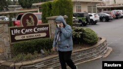 La epidemia del coronavirus, que se originó en China, ha cobrado ya 6 muertes en EE.UU. En la foto, una mujer pasa por delante del anuncio del centro hospitalario Kirkland, estado de Washington, donde se han confirmado varios casos.