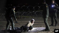 FILE - In this Nov. 30, 2018 file photo, U.S. Border Patrol detain Honduran migrants after they walked onto U.S. territory from Tijuana, Mexico.