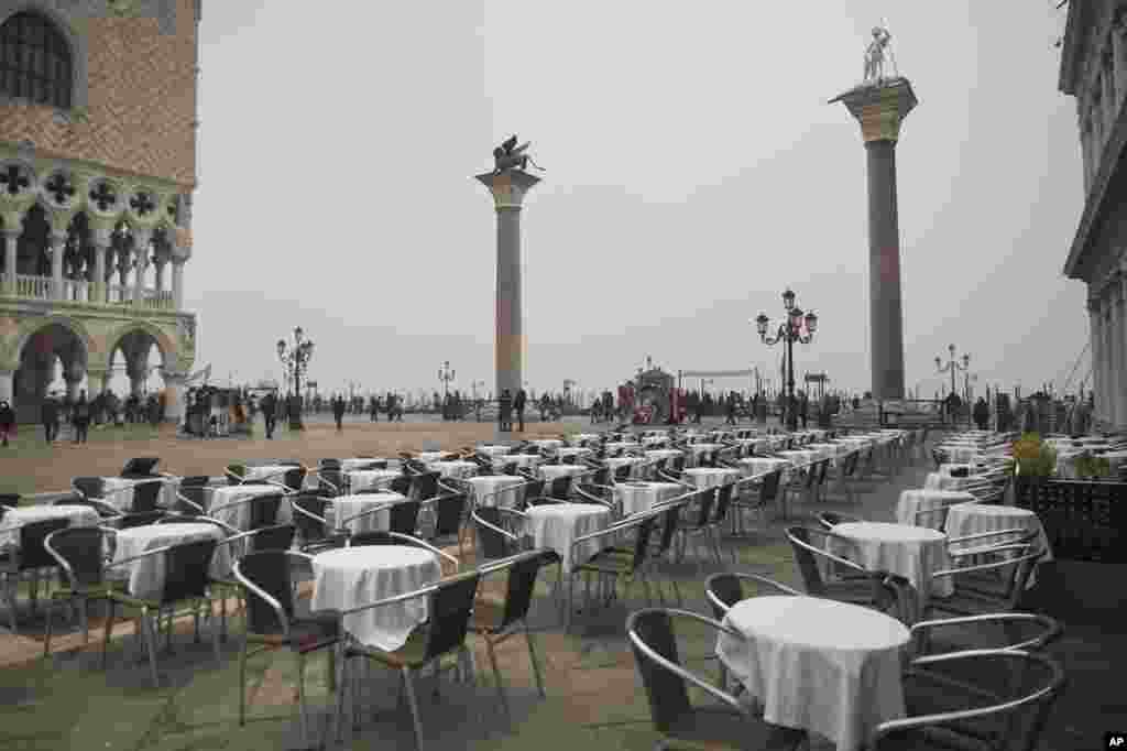 Empty tables sit in St. Mark&#39;s square in Venice, Italy. Italy has been working to slow the spread of Europe&#39;s first major outbreak of the new coronavirus. It has called off the popular Venice Carnival and closed major tourist attractions.