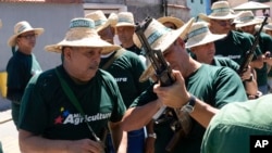 Trabajadores públicos revisan sus rifles antes de un desfile de los "cuerpos combatientes" en Caracas, el 7 de enero de 2025.