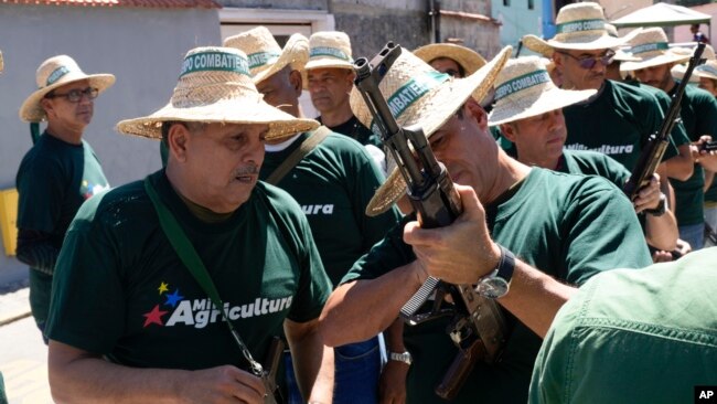 Trabajadores públicos revisan sus rifles antes de un desfile de los "cuerpos combatientes" en Caracas, el 7 de enero de 2025.