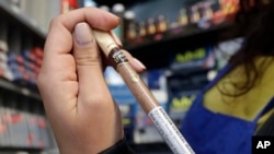 En esta foto del 17 de mayo de 2018, Miriam Zouzounis sostiene un cigarrillo Black & Mild Wine mientras era entrevistada en Ted's Market, la tienda de su familia, en San Francisco. Zouzounis, miembro del directorio de la Asociación de Tenderos Árabe-Estadounidenses, que representa a 400 propietarios de pequeñas empresas en el área de la bahía de San Francisco, dijo que la prohibición del tabaco con sabor eliminaría un producto ancla que atrae a clientes. (AP Photo / Jeff Chiu)