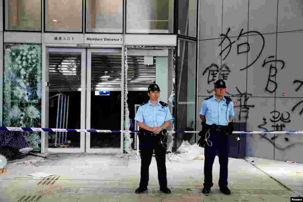 香港警察2019年7月2日站在立法會外，可以看到外牆上被抗議者在前一晚示威時塗寫的塗鴉。