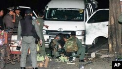 Members of the Thai bomb squad inspect an area after a grenade exploded on Rangnam road near a duty-free shopping centre in Bangkok, 30 July 2010