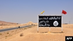 A general view taken on August 13, 2017 shows an Islamic State (IS) group poster in the central Syrian town of Al-Sukhnah. Pro-government fighters cleared the area after taking control of the county's large desert area called the Badiya.