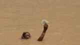A flood victim holds an item above water as she attempts to reach higher ground on the outskirts of Patna, India.