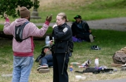 San Francisco Police Officer Kathleen Cavanaugh talks to a man, May 24, 2017, while patrolling Golden Gate Park in San Francisco. Courts around the country tried to ease the burden of fines and fees in the wake of riots in Ferguson, Mo., in 2014.