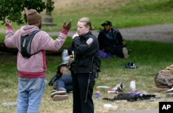 San Francisco Police Officer Kathleen Cavanaugh talks to a man, May 24, 2017, while patrolling Golden Gate Park in San Francisco. Courts around the country tried to ease the burden of fines and fees in the wake of riots in Ferguson, Mo., in 2014.
