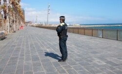 A police officer stands guard preventing access to the beach in Barcelona, Spain, March 15, 2020.
