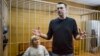 Russian opposition leader Alexei Navalny gestures while speaking, as his lawyer Olga Mikhailova listens, in court in Moscow, Russia, March 27, 2017. 