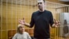 Russian opposition leader Alexei Navalny gestures while speaking, as his lawyer Olga Mikhailova listens, in court in Moscow, Russia, March 27, 2017. 