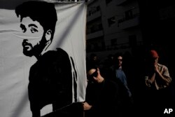 A large banner depicts Hersh Goldberg-Polin as families and supporters of Israeli hostages held by Hamas call for their return outside a meeting between U.S. Secretary of State Antony Blinken and Israeli President Isaac Herzog in Tel Aviv on Jan. 9, 2024.