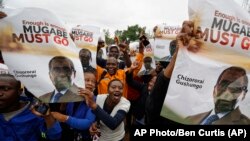 Para pengunjuk rasa memegang poster yang menyerukan agar Presiden Mugabe turun dari jabatannya dalam aksi demo di Zimbabwe Grounds, Harare, Zimbabwe, Sabtu, 18 November 2017.