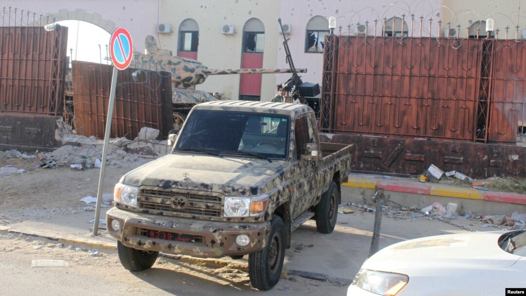 Seorang anggota pasukan keamanan yang setia kepada pemerintah Libyan yang didukung PBB mengendarai pickup di penjara Al-Hadba yang rusak saat baku tembak dengan faksi saingan di distrik Abu Salim, di Tripoli, Libya, 28 Mei 2017. (Foto: Hani Amara/Reuters)