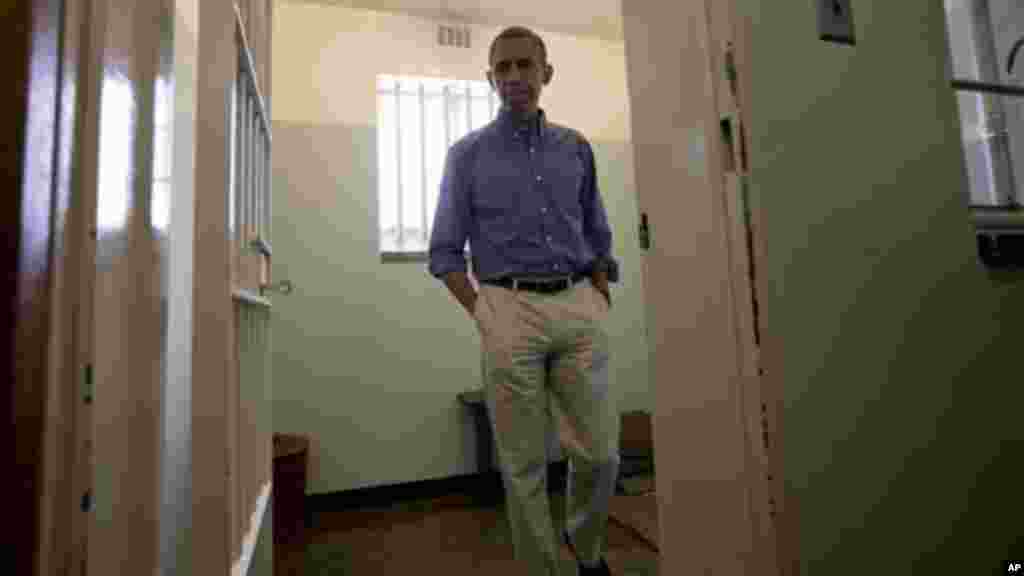 President Obama walks from Mandela's prison cell No. 5, on Robben Island.