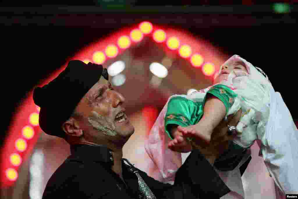 A Shi&#39;ite Muslim holds a child as he takes part in an Ashura procession in the holy city of Kerbala, Iraq.