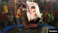 Children of supporters of deposed Egyptian president Mohamed Morsi jump on a trampoline in a makeshift funfair in Cairo's Rabaa al-Adawiya Square, August 11, 2013.