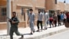 FILE - Islamic State prisoners walk behind a Kurdish policeman in Ain Issa village, north of Raqqa, Syria, June 24, 2017.