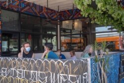 Patrons observing social distancing rules sit outdoors at the Guerrilla Tacos restaurant in Los Angeles, July 3, 2020.