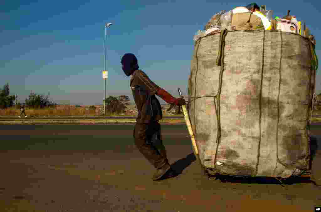 A man pulls a trolley filled with cardboard and plastic bottles for recycling on a street in Phumlamqashi informal settlement near Johannesburg, South Africa.